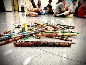 Colorful folk dance sticks in a pile on shiny multipurpose room floor at a school.
