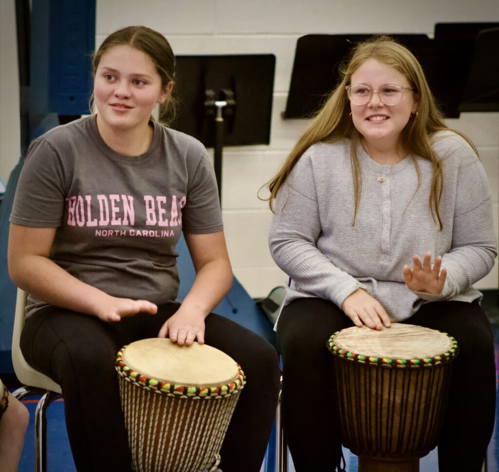 Close-up of two students smiling while learning to play djembe.