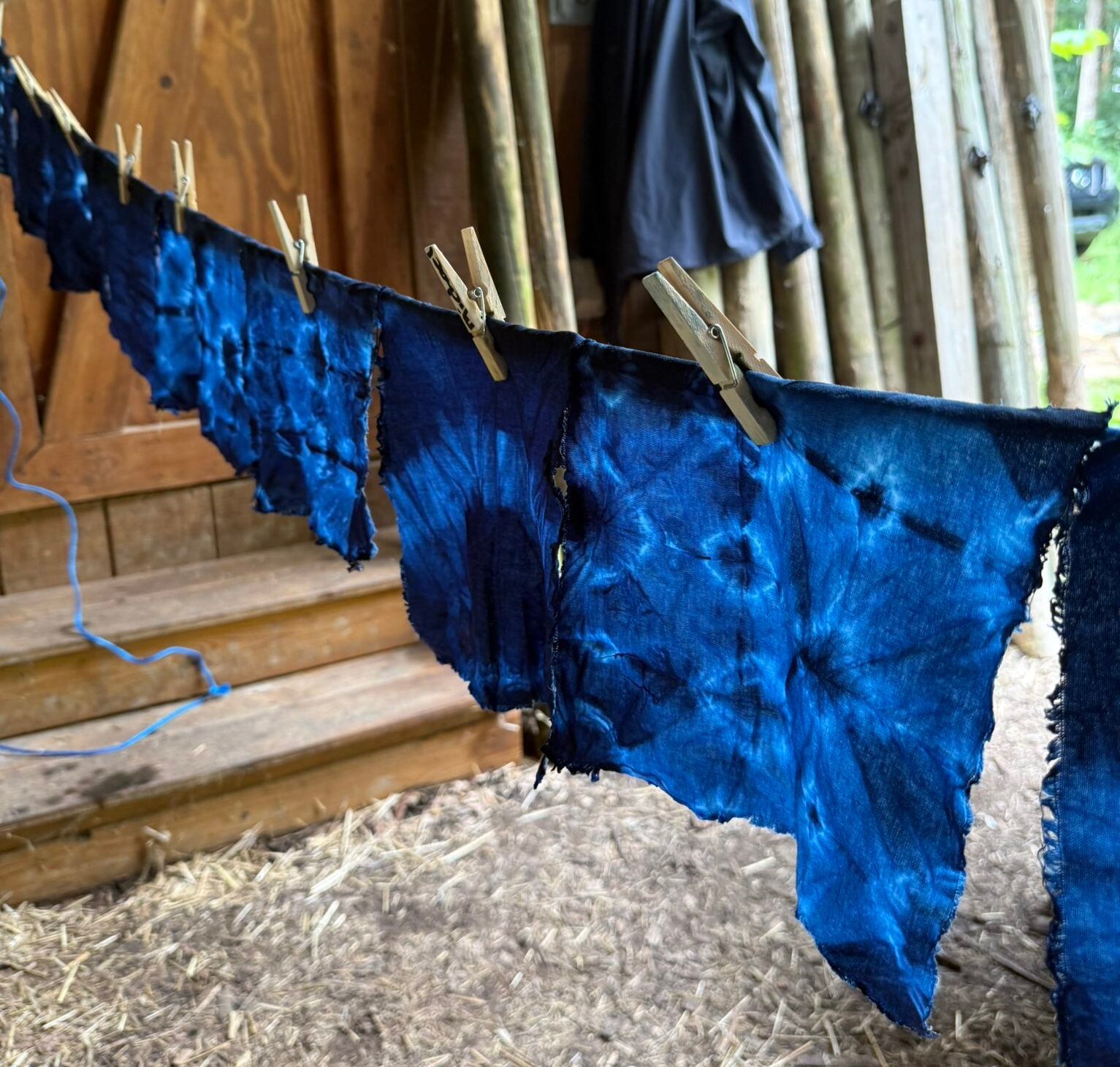 Indigo dyed fabric hanging on a clothing line in a shed