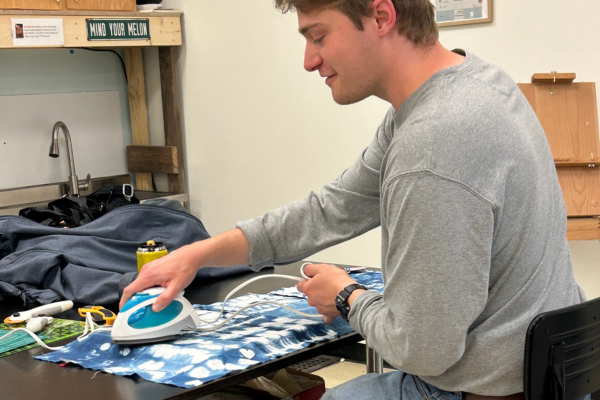 A person is ironing a blue and white patterned fabric on a table.