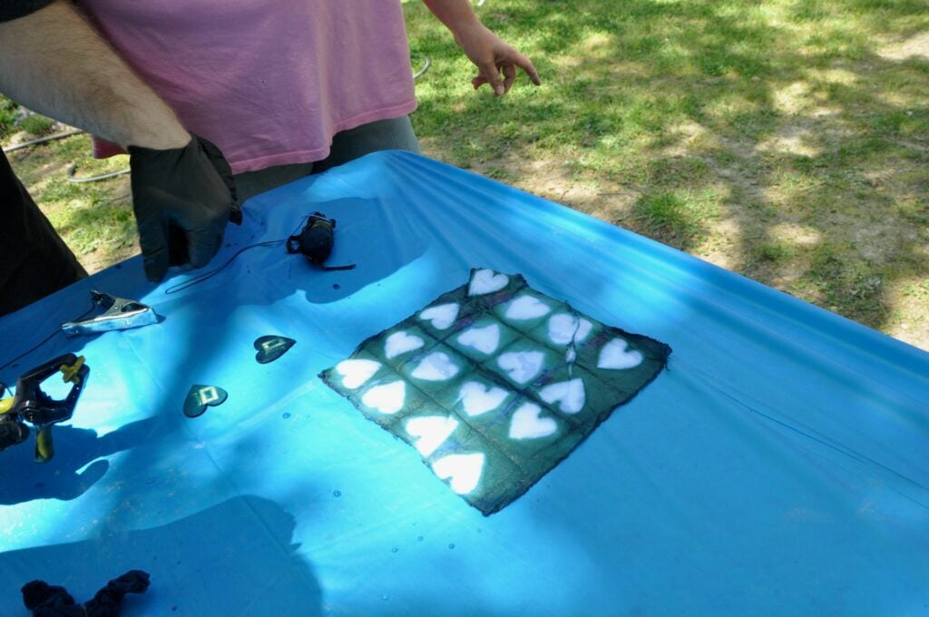 Indigo dyes blue quilt square with heart pattern laying on table with light blue table cloth
