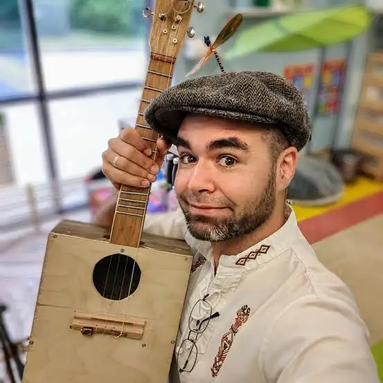 Luke Vandergriff holding a handmade guitar, smiling at the camera